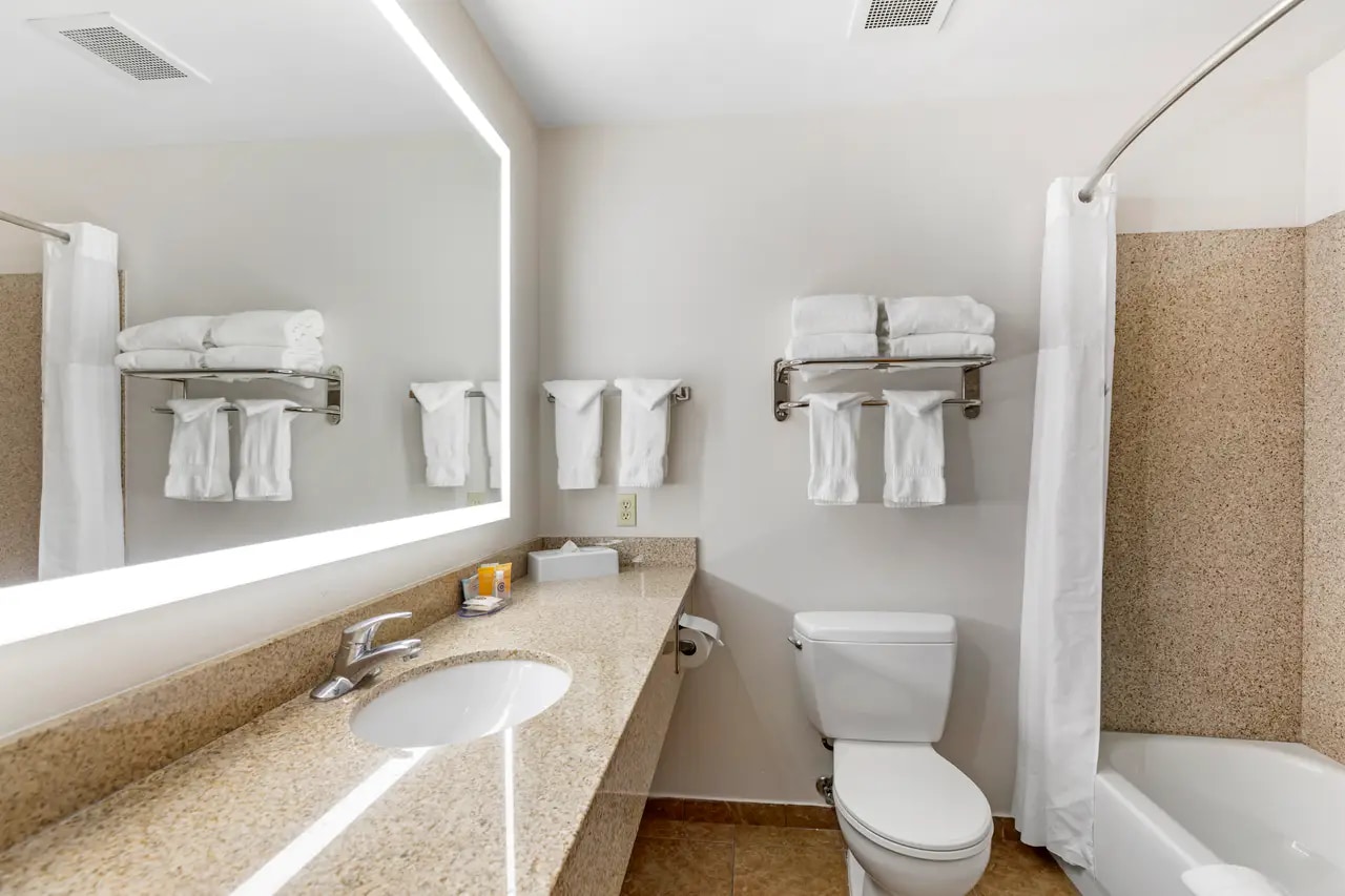 Clean hotel bathroom with illuminated mirror and vanity